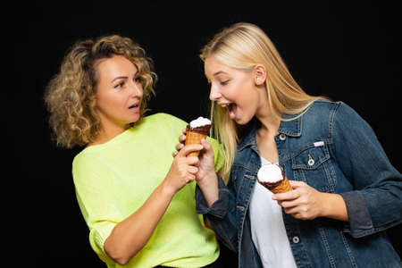 Mom and daughter eat ice cream, laugh, rejoice, close-up, on a black background.の写真素材