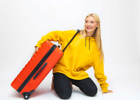 Traveling with a suitcase, happy, cheerful, beautiful blonde under an umbrella, white background, close-up.の写真素材