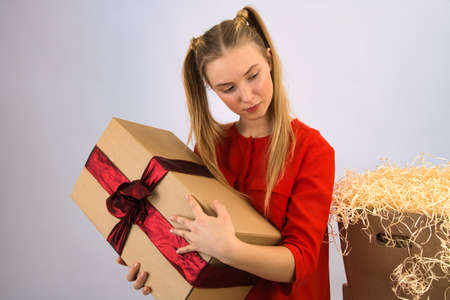 the girl is very happy and delighted with the box with gifts