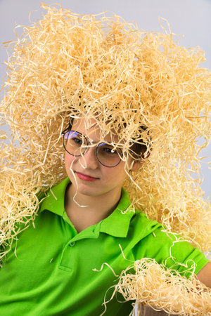 Boy with glasses in a green T-shirt, with sawdust on his headの写真素材