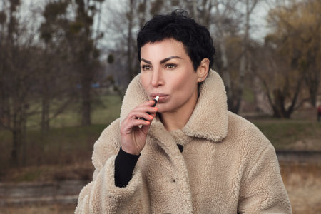 Stylish girl with a pensive look smokes an electronic cigarette