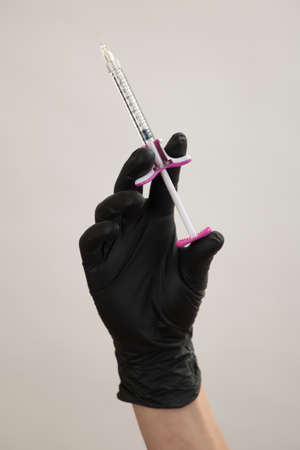 A hand in a black glove holds an injection syringeの写真素材