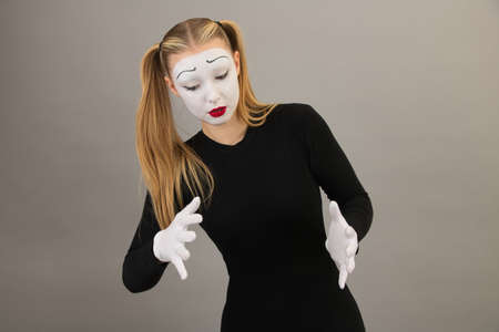 The girl-artist in the role of pantomime holds an invisible ball.