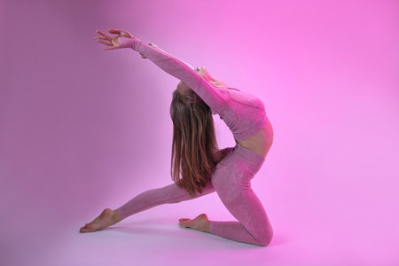 A dancer demonstrates dance warm-up movements in the style of modern dance on a pink background.の写真素材