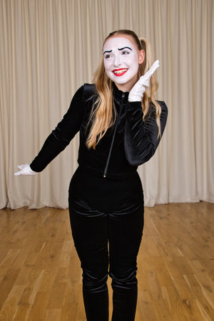 Portrait of a smiling female mime in a black dress and white gloves.の写真素材