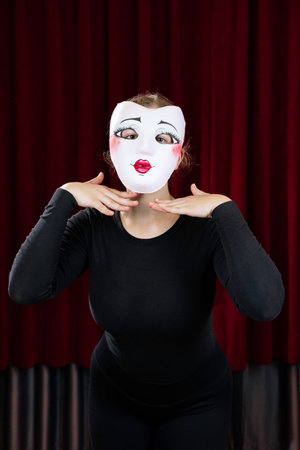 A mime girl in a white mask against a red curtain. Close-up.の写真素材