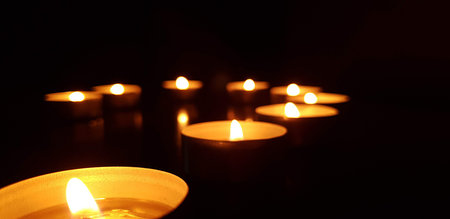 A warm and serene composition of burning candles creating soft light and cozy atmosphere. Perfect for meditation, spirituality, reflection, or romantic mood.の写真素材