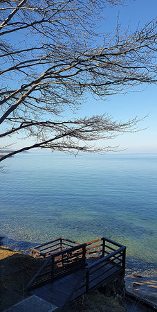 Beautiful winter landscape of Lake Baikal in Siberia with a wooden platform overlooking the calm blue surface of the water and a clear sky. Symbol of peace, freedomの写真素材