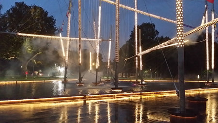 Night view of an illuminated modern fountain in Ventspils, Latvia, with water mist and reflections creating an atmospheric and artistic urban scene.の写真素材
