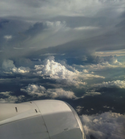 View from airplane window showing the aircraft engine and a dramatic sky full of clouds. Aerial scene symbolizing travel, adventure, and freedom above the clouds.の写真素材