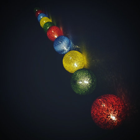 Artistic close-up of multicolor glowing string lights in the dark. Decorative LED spheres creating warm and cozy atmosphere, ideal for backgrounds, design, or celebration projects.の写真素材
