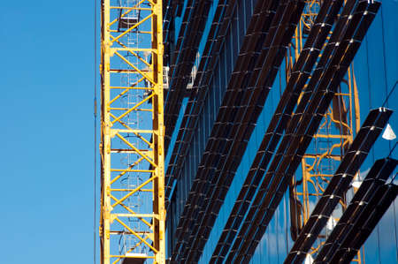 Building crane against mirror windows on building siteの写真素材