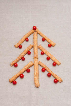 Christmas card, tree made of grissini and cherry tomatoes on linen fabricの写真素材