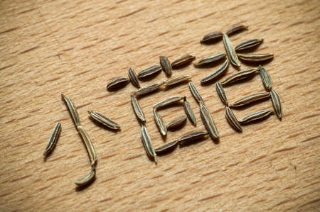 Cumin written in Chinese characters with cumin seeds on wood close upの写真素材
