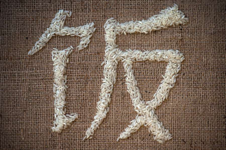 Rice written in Chinese characters with rice grains on sack background close upの写真素材