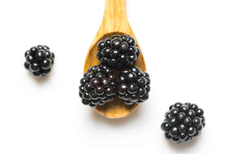 Ripe blackberries in wooden spoon on white backgroundの写真素材
