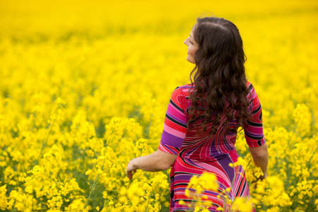 Vibrant yellow canola field and cheerful girl, spring feeling from Latvia, Baltic statesの写真素材