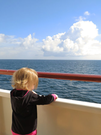 Little girl on the deck of a cruise ship looking at the horizonの写真素材