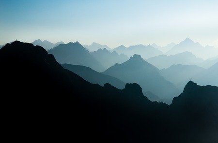 Spectacular blue and cyan mountain ranges silhouettes. Summit crosses visible.の写真素材