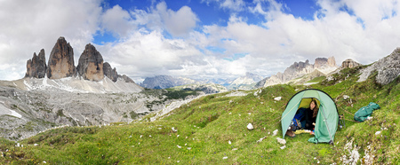 Woman sitting in tent smiling happy. Great mountains. Tre Cime.の写真素材