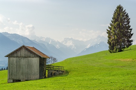 View from wooden barn to snow covered mountains in springtimeの写真素材