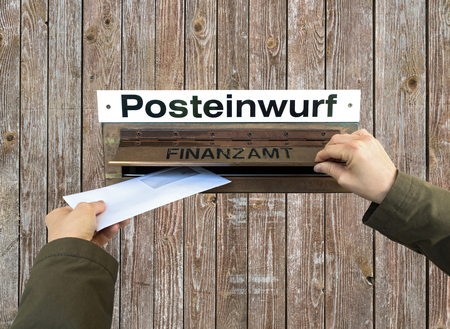 Hands post a letter into letterbox of finance office, Finanzamt.の写真素材