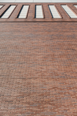 Red brick wall facade background with high windows. Industrial buildingの写真素材
