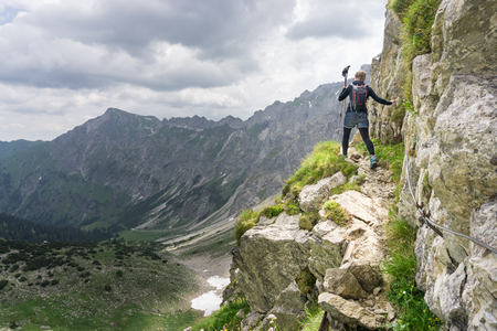 Woman walks on dangerous trail in alpine mountains.の写真素材