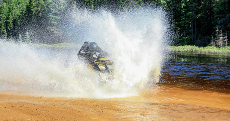 Man driving ATV quad through splashing water with high speed.の写真素材