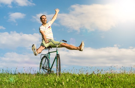 Happy winning man on bicycle. Legs and arms raised up.