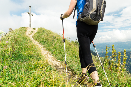 Woman running on narrow mountain trail with hiking poles.の写真素材