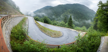 Winding mountain road in a forest. Foggy wet weather and slippery asphalt. Alps, Slovenia.の写真素材