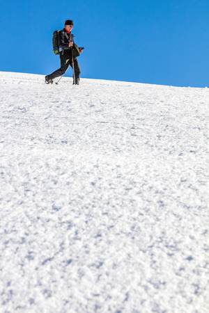 Man is snowshoe hiking through deep snow on sunny dayの写真素材