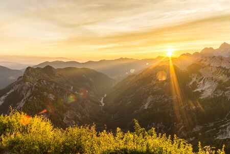Amazing sunrise in the mountains. Backlight Sunlight with beautiful lens flares and sunbeams. Julian Alps, Triglav National Park, Slovenia, Mountain Slemenova, Sleme.の写真素材
