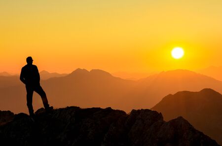 Happy success winning man standing relaxed on mountain at sunset. Border region of Tyrol, Austria and Allgaeu, Bavaria, Germany.の写真素材