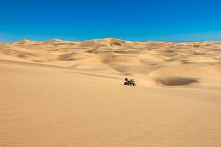 Quad driving in sand desert. Quadbike stand in the middle of nowhere. Panoramic desert view. Africa.の写真素材