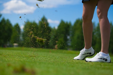 A golfer strikes a tee shot on a beautiful park near lakeの写真素材