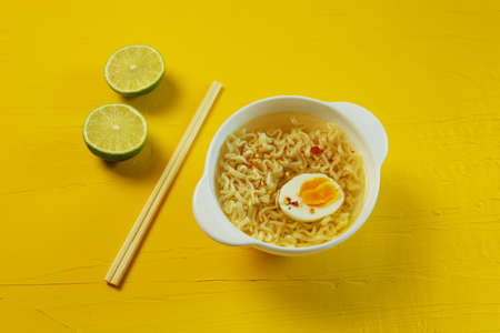 Egg noodles on a yellow background with lime and chopsticks.の写真素材