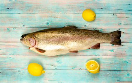 Rainbow trout and lemons on a wooden background.