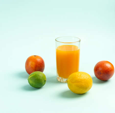 Juice in a tall glass surrounded by fruits. Blue background. Horizontal orientationの写真素材