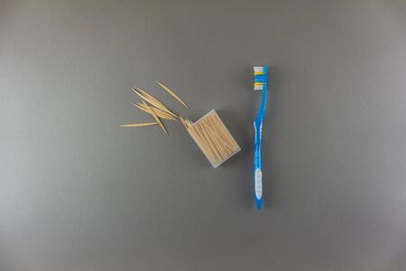 Messy arranged toothpicks with toothbrush on gray background