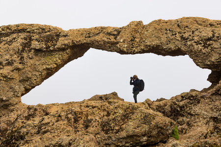 The view of the photographer taking photo through Ventana del Nublo on the cloudy day.の写真素材