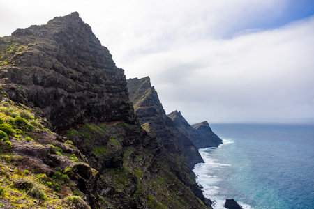 Four mountains raised from the ocean on a cloudy day. Waves hitting on the rock on the shore. no people.の写真素材