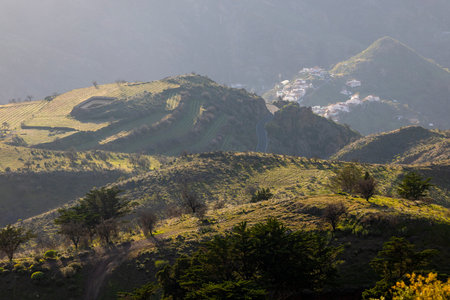 Landsape photo of winding road in tho Gran Canaria's moutains with Tenerifa's Teide view. Daylight, some clouds, and some traffic. no people. Small city with white houses.の写真素材