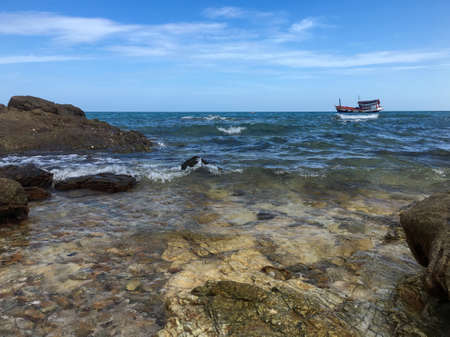 view of sea , rock and boat with blue sky for backgroundの写真素材