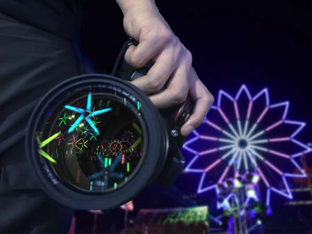 male hand holding camera that have reflect beautiful light on lens with light turbine background