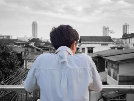 back view of lonely man in color with black and white tone cityscape backgroundの写真素材