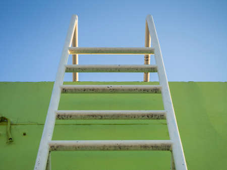 under view of steel ladder on green background and blue sky