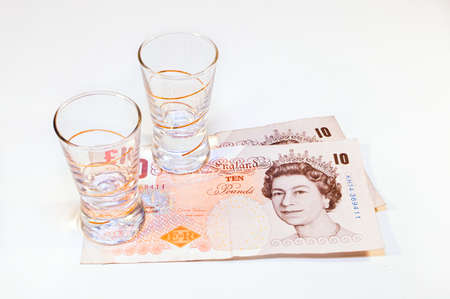 two vodka glasses on banknotes ten poundsの写真素材