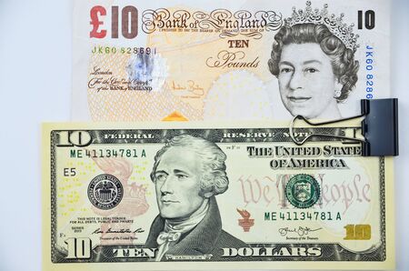 british pounds and us dollars banknotes stapled togetherの写真素材